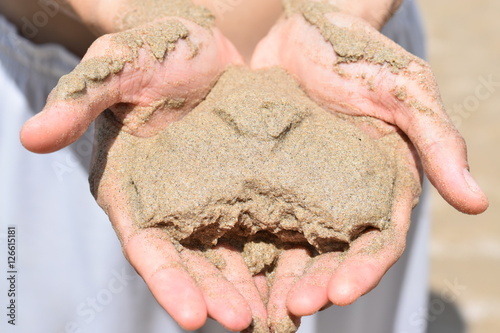 two hands holding sand in the shape of a heart