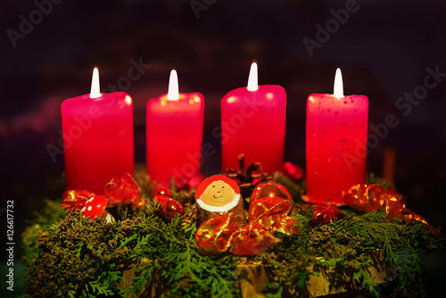 Weihnachtskranz mit vier roten brennenden Kerzen und Wichtel