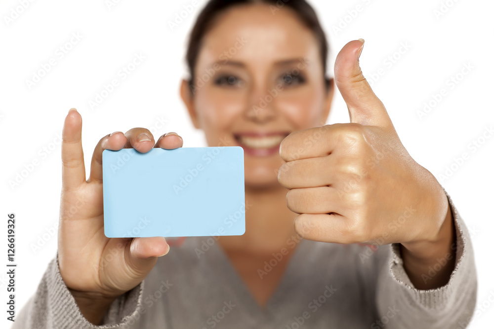 young smiling woman holding a plastic credit card on a white background and showing thumbs up young smiling woman holding a plastic credit card on a white background and showing thumbs up