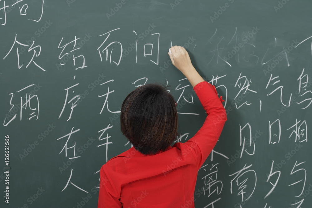 woman writing Chinese characters on chalkboard woman writing Chinese characters on chalkboard