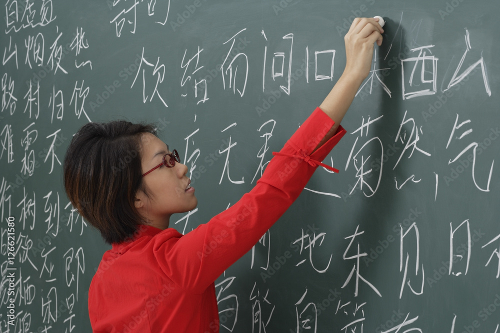 woman writing chinese characters on chalk board