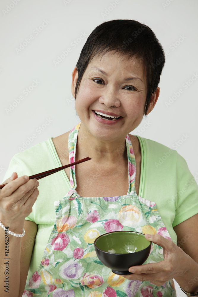 Mature Chinese woman holding chopsticks and bowl Mature Chinese woman holding chopsticks and bowl