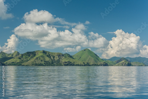 Open spaces are located in the green hills under a blue sky with white clouds near the calm sea (Singapore)