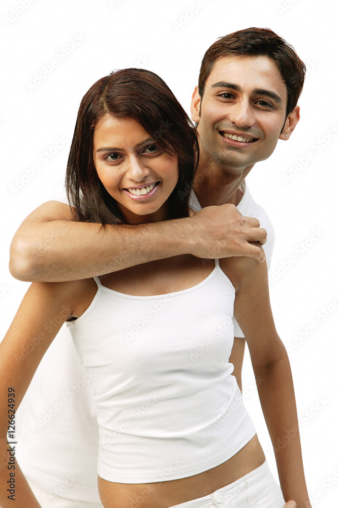 Man hugging woman from behind, both looking at camera Man hugging woman from behind, both looking at camera