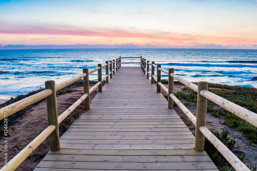 Wooden walkway on the Atlantic ocean coast in the sunset time in Alentejo, Portugal