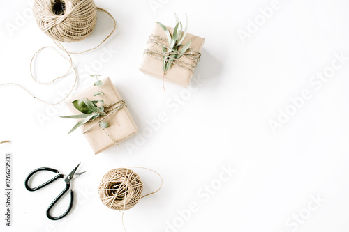 creative arrangement pattern of craft boxes and green branches on white background. flat lay, top view