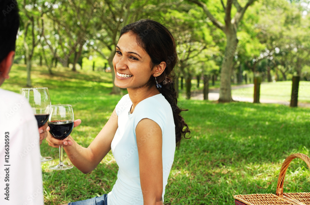 Couple in park, toasting with wine glasses Couple in park, toasting with wine glasses