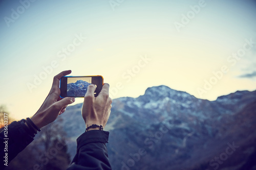 Ragazzo scatta foto in montagna con smartphone photo