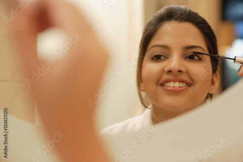 Woman looking in mirror applying mascara Free Download Woman looking in mirror applying mascara - GFXLoad
