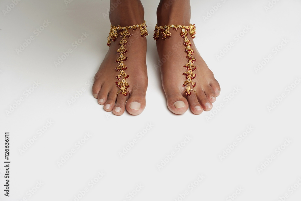 Woman's feet with anklet against white floor