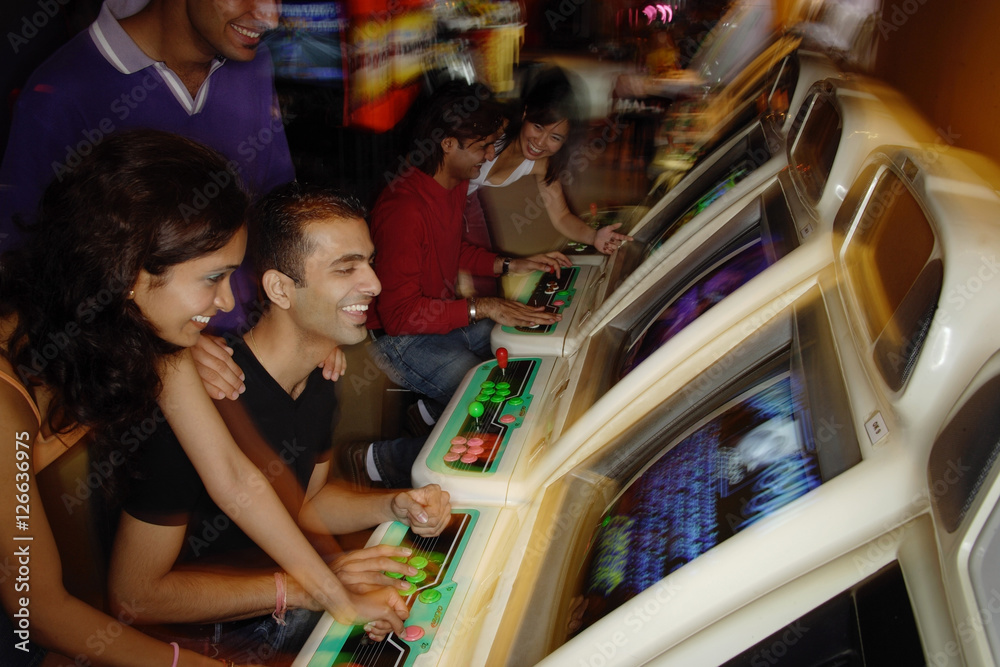 Young adults playing games in video arcade