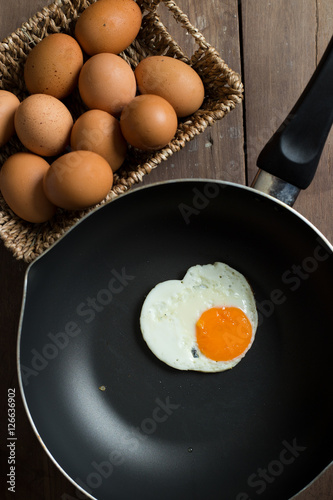 Fried egg on pan and fresh eggs.