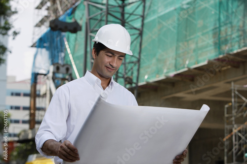 Man with helmet, looking at plans