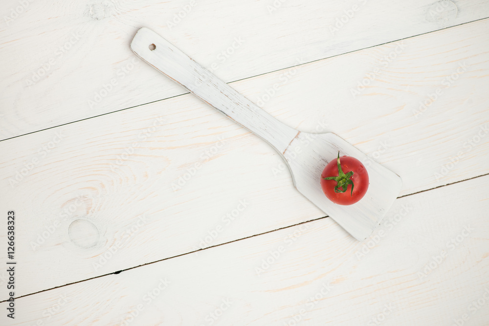 tomato on wooden spoon on white old wooden boards tomato on wooden spoon on white old wooden boards