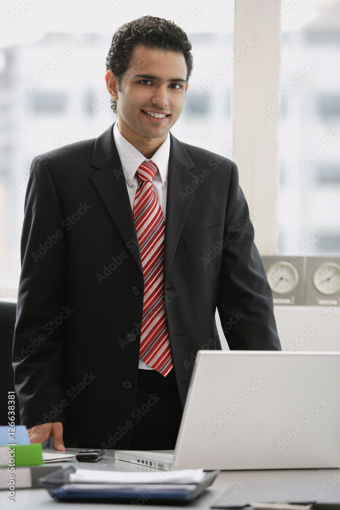 Businessman standing in office, looking at camera Businessman standing in office, looking at camera