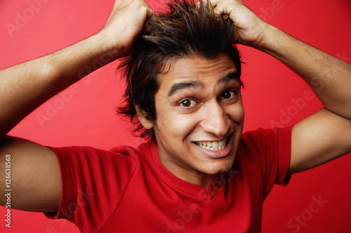 Tapet Man in red T-shirt against red background, pulling hair
