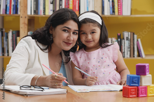 Woman and girl with books, looking at camera