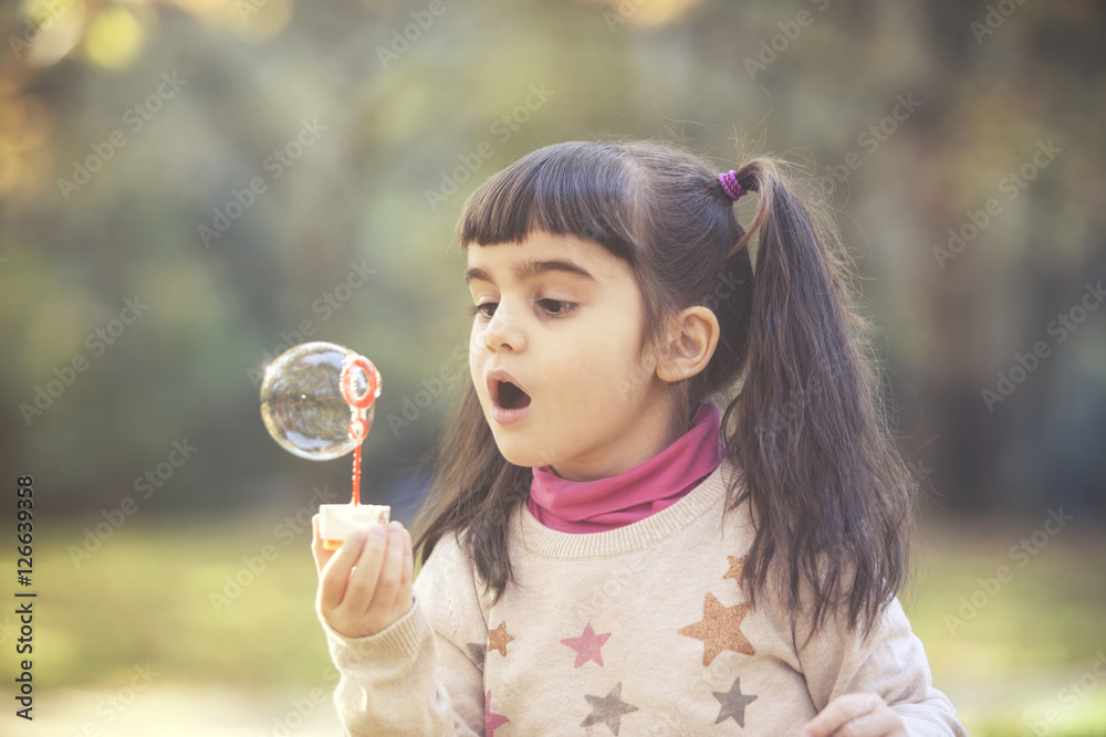 Cute little girl blowing soap bubbles in the park Cute little girl blowing soap bubbles in the park
