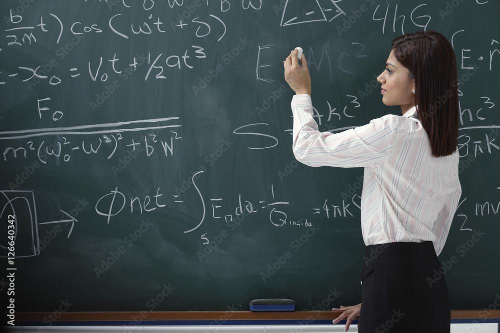Woman writing equations on chalk board