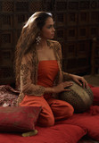 Young woman relaxing on pillows with Indian antiques