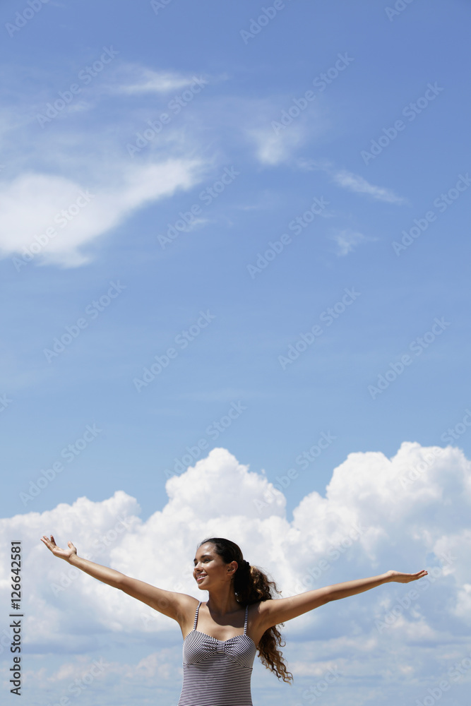 happy young woman raising her arms, blue sky and clouds background. happy young woman raising her arms, blue sky and clouds background.