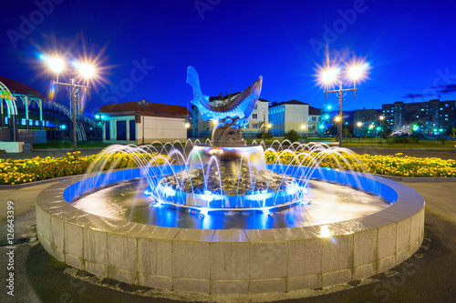 Fountain with fish Sturgeon in the evening illumination . Langepas .