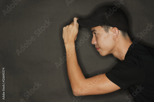 Photography Young man touching cap, black background