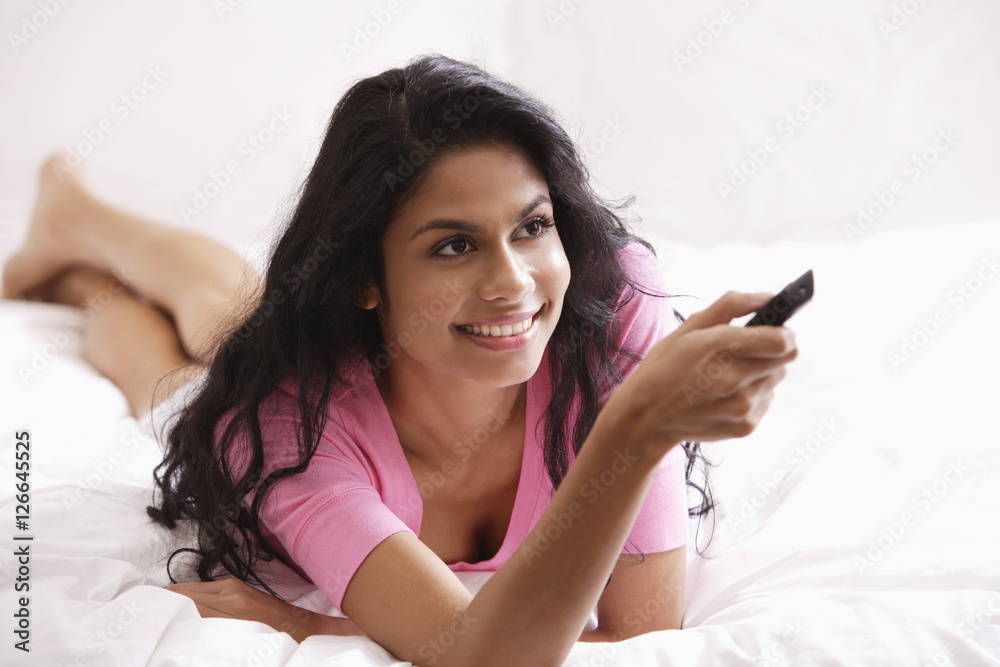 Indian woman laying on bed watching TV Indian woman laying on bed watching TV