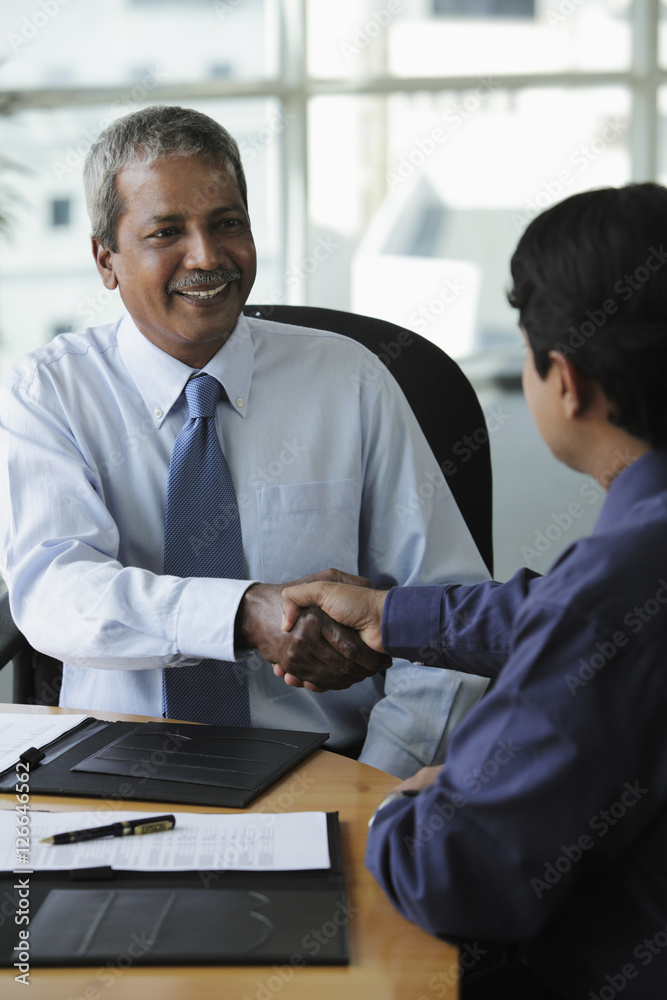 Indian business men shaking hands and smiling