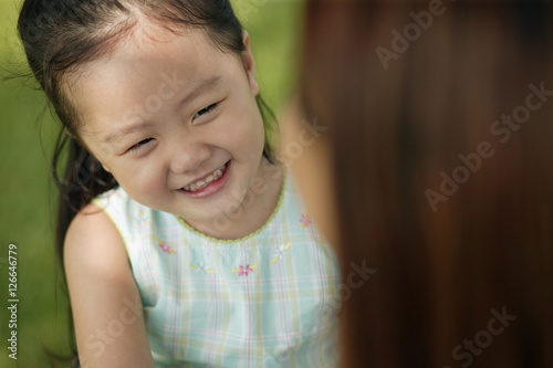 Young girl smiling, mother looking on