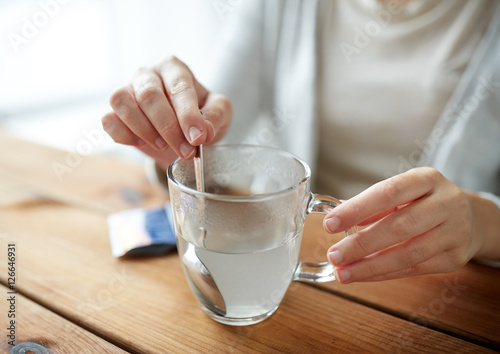 woman stirring medication in cup of water photo