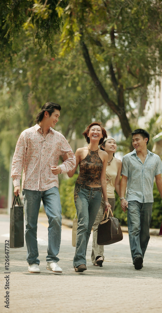 Couples walking hand in hand, carrying shopping bags Couples walking hand in hand, carrying shopping bags