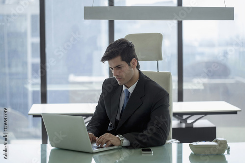 India, Businessman sitting at desk using laptop