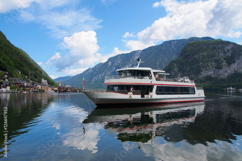 The ferry goes across lake Hallstatt, mountains as background, Austria. photo