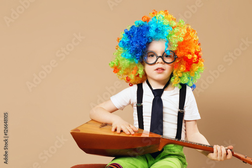 Blithesome children. Happy clown boy in large neon colored wig p