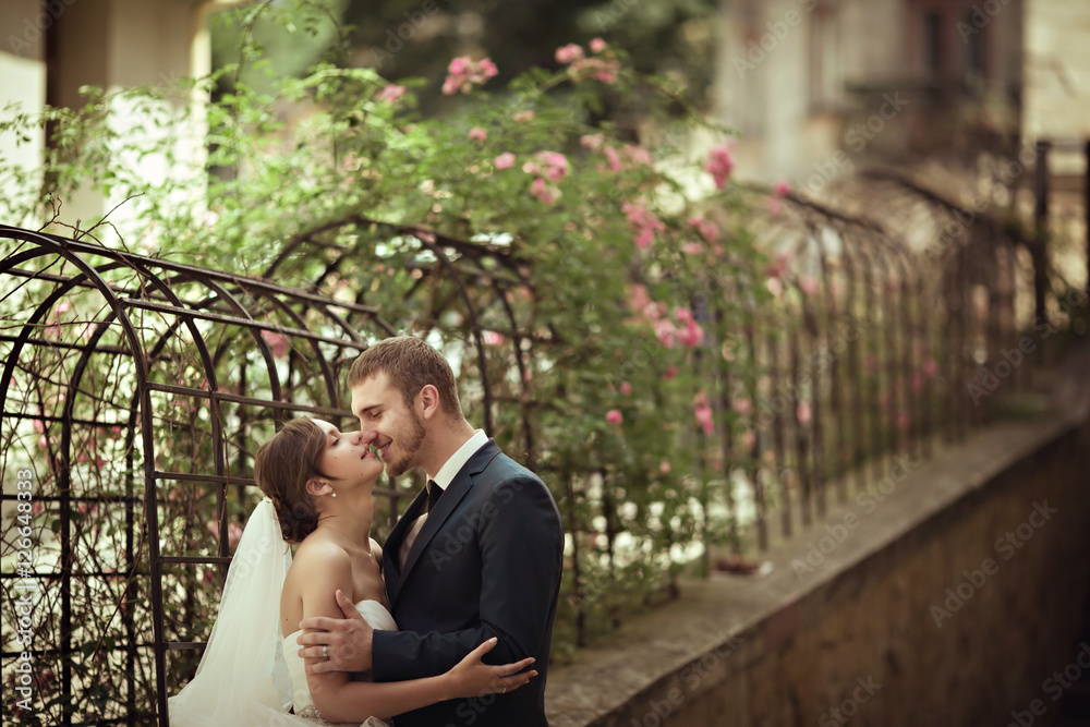 Happy wedding couple is posing in city garden Happy wedding couple is posing in city garden