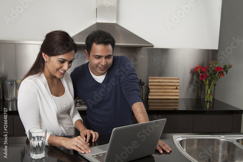 Canvas Print Singapore, Young couple using laptop in kitchen