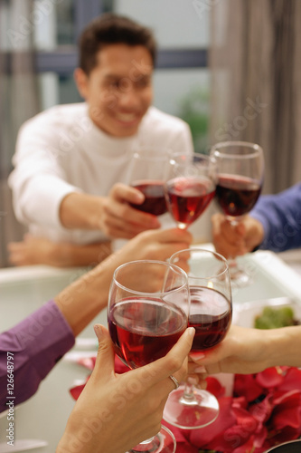 Obraz na płótnie Friends toasting with wine glasses across dinner table w salonie