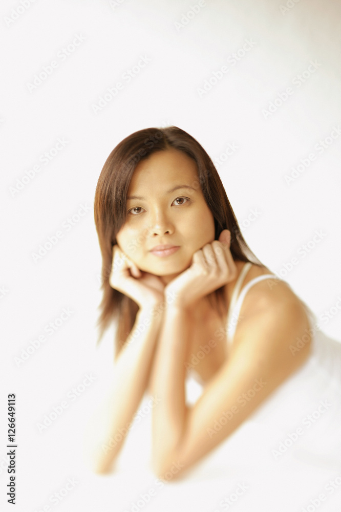 Young woman lying on floor, hands on chin, looking at camera