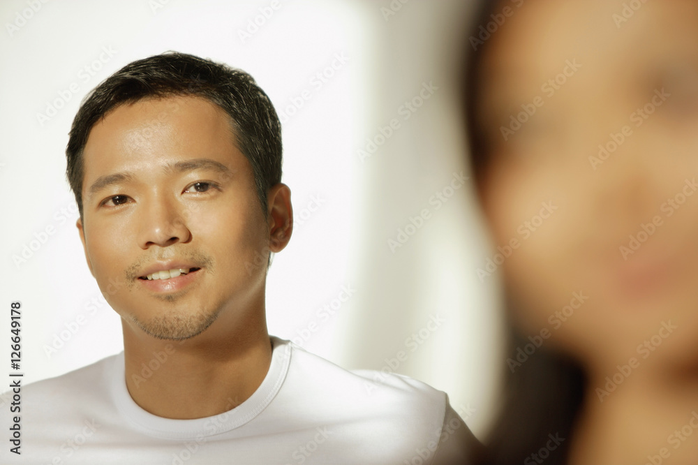 Young man looking at camera, woman in front of him Young man looking at camera, woman in front of him