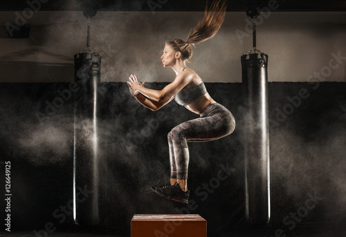 sporty girl jumping over some boxes in a cross-training gym
