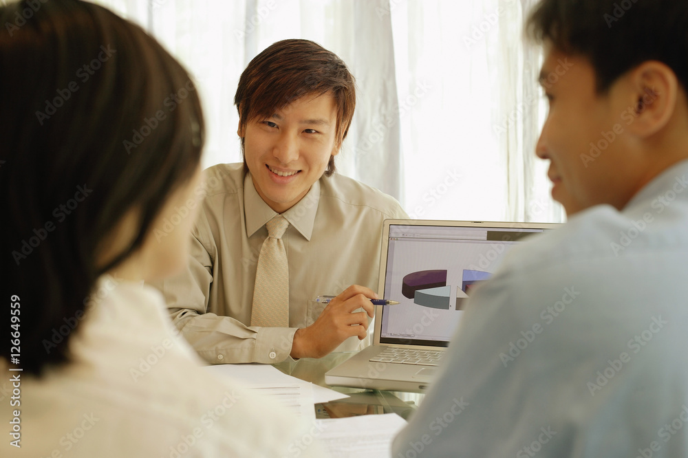 Obraz premium Young man showing laptop screen to couple in front of him