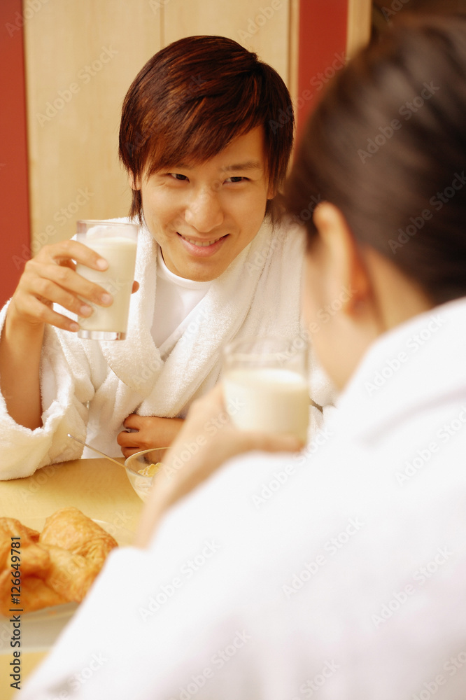 Couple sitting across each other drinking milk Couple sitting across each other drinking milk