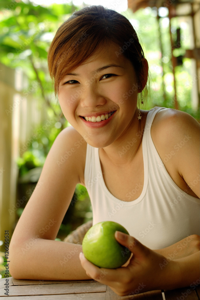Woman holding an apple, looking at camera Woman holding an apple, looking at camera