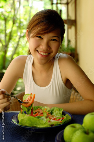 Woman eating salad  looking at camera