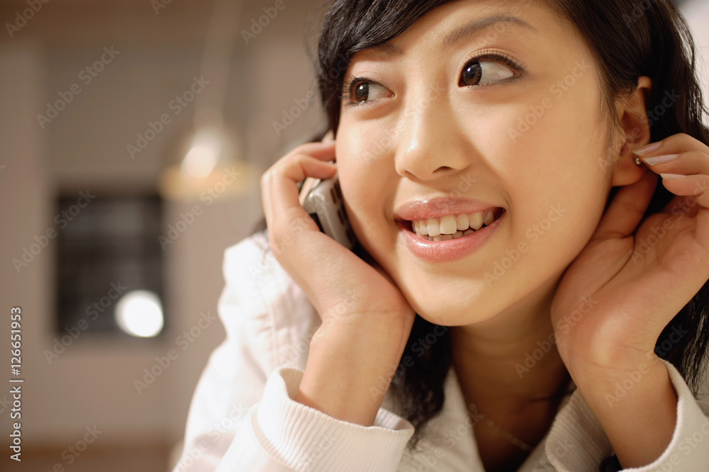 Young woman using mobile phone, touching ear and looking away Young woman using mobile phone, touching ear and looking away