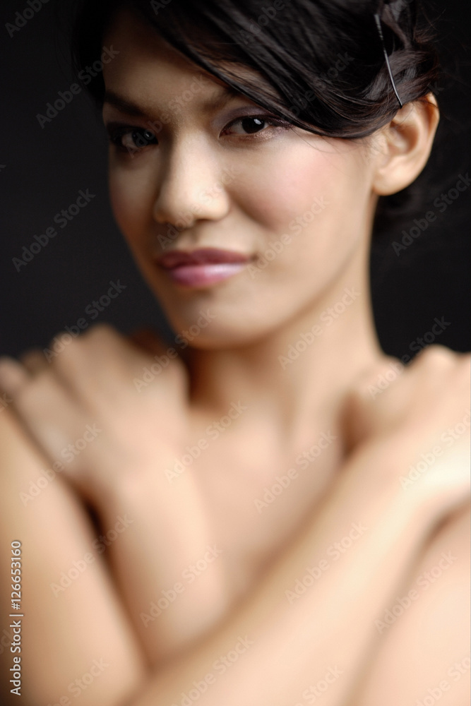 Portrait of a young woman, arms crossed over chest, looking at camera Portrait of a young woman, arms crossed over chest, looking at camera