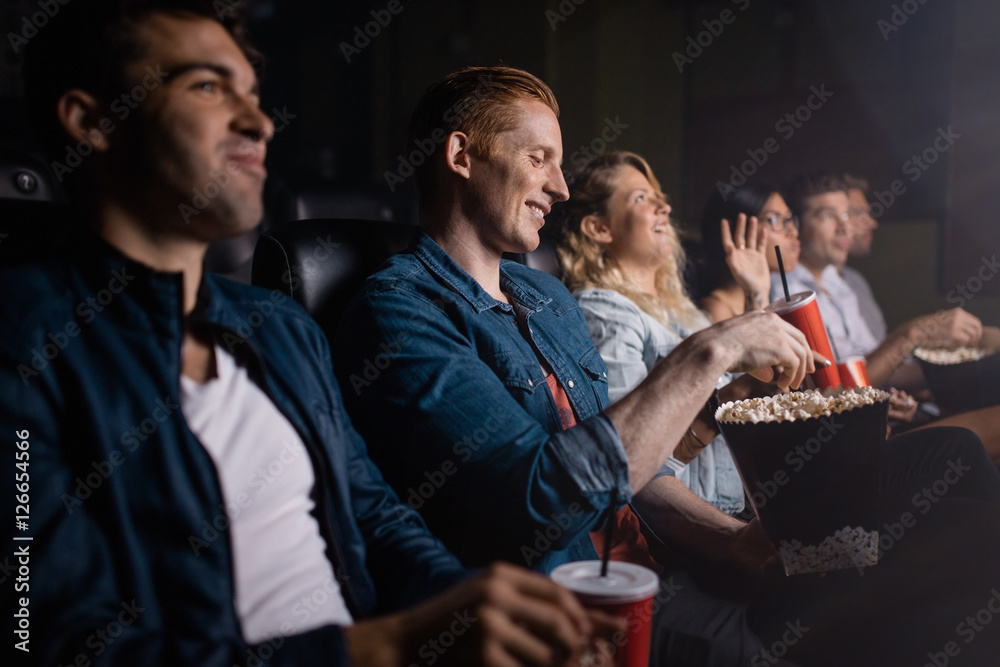 Young man with friends watching movie in cinema - obrazy, fototapety, plakaty 