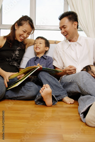 Family with one son sitting together, looking at book