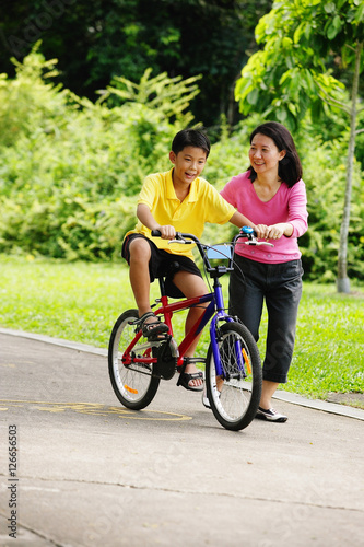 Son on bicycle, mother next to him